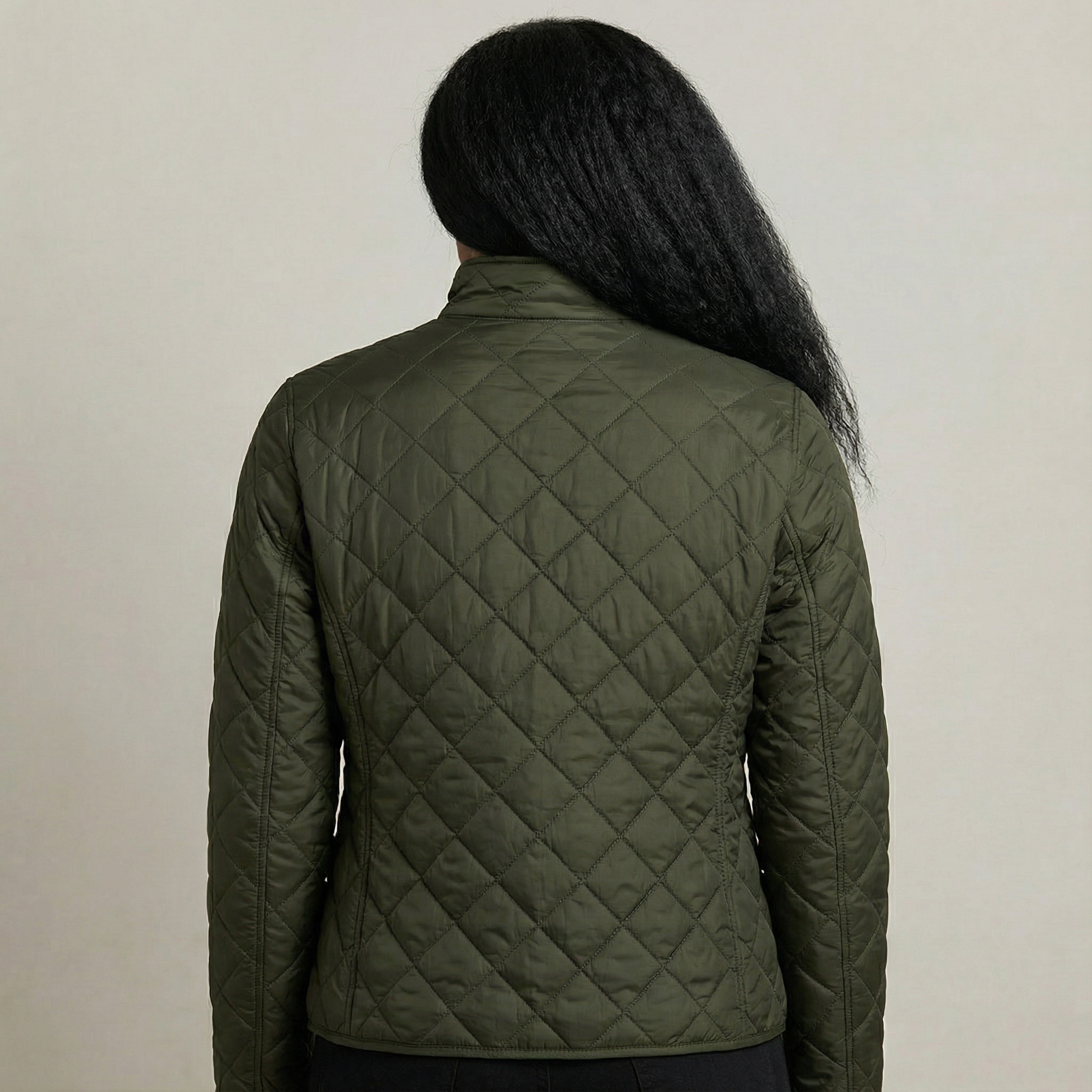 Person wearing a green quilted jacket against a neutral background