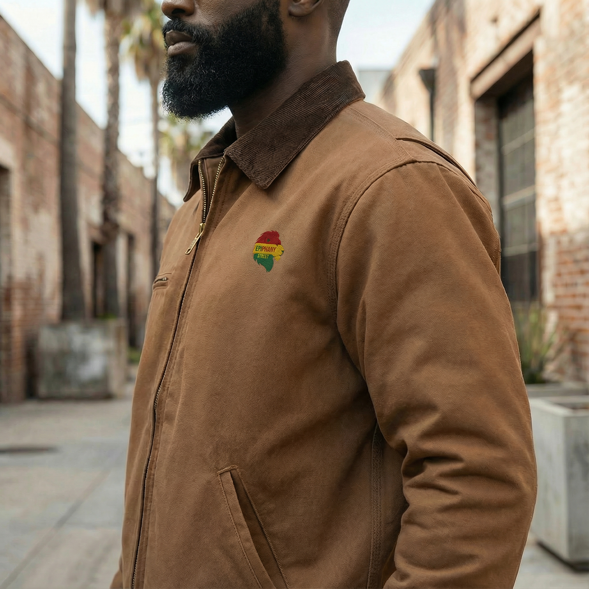 Man wearing a brown jacket with a colorful patch on a street.