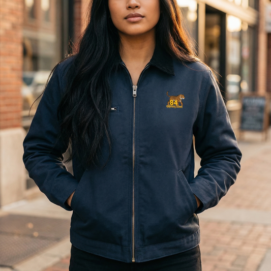 Person wearing a navy blue jacket with a logo on a city street