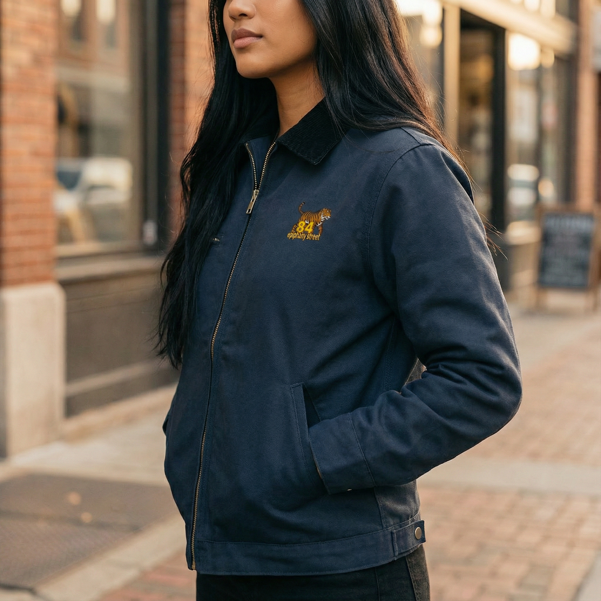 Person wearing a navy blue jacket with a logo on a city street
