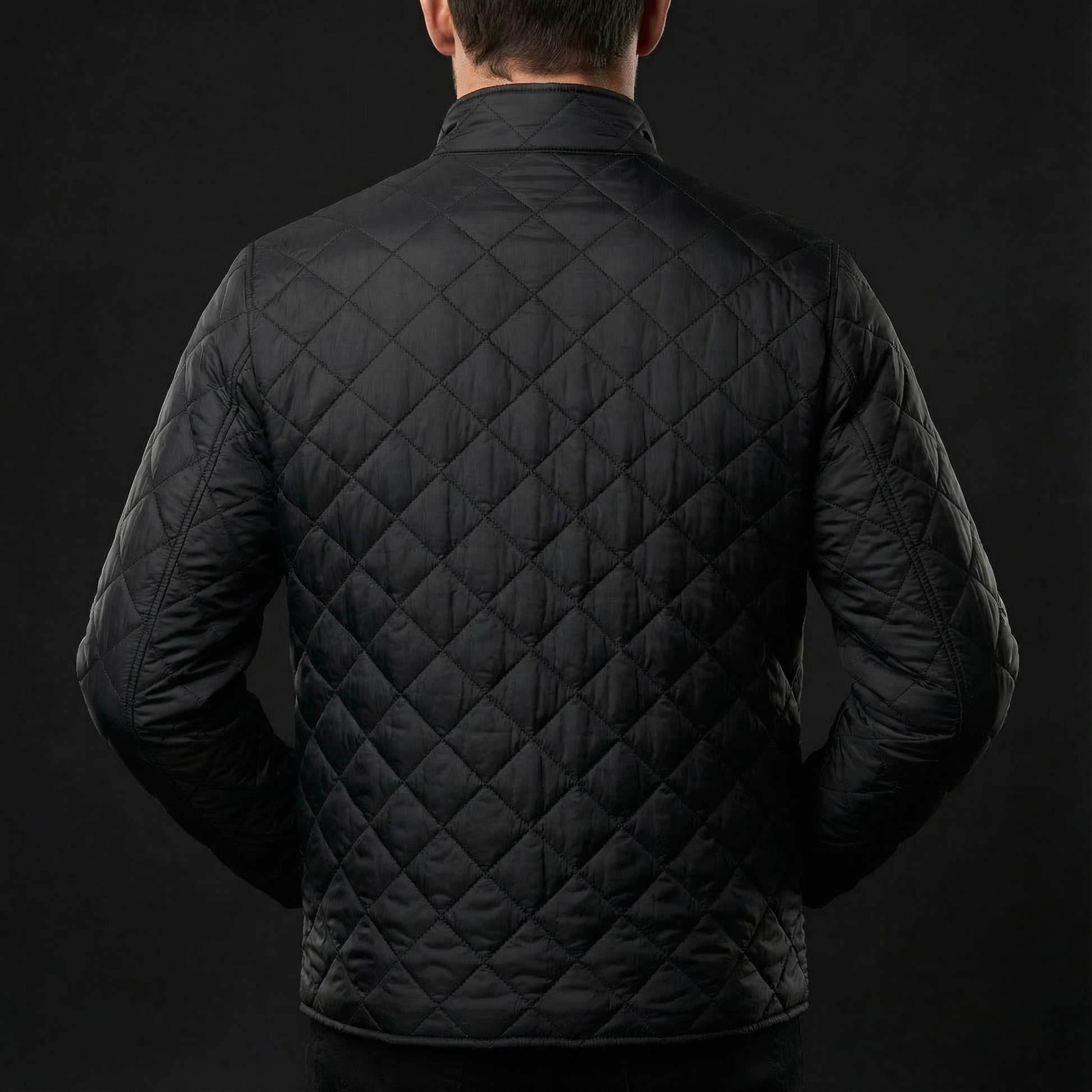 Black quilted jacket worn by a person on a black background