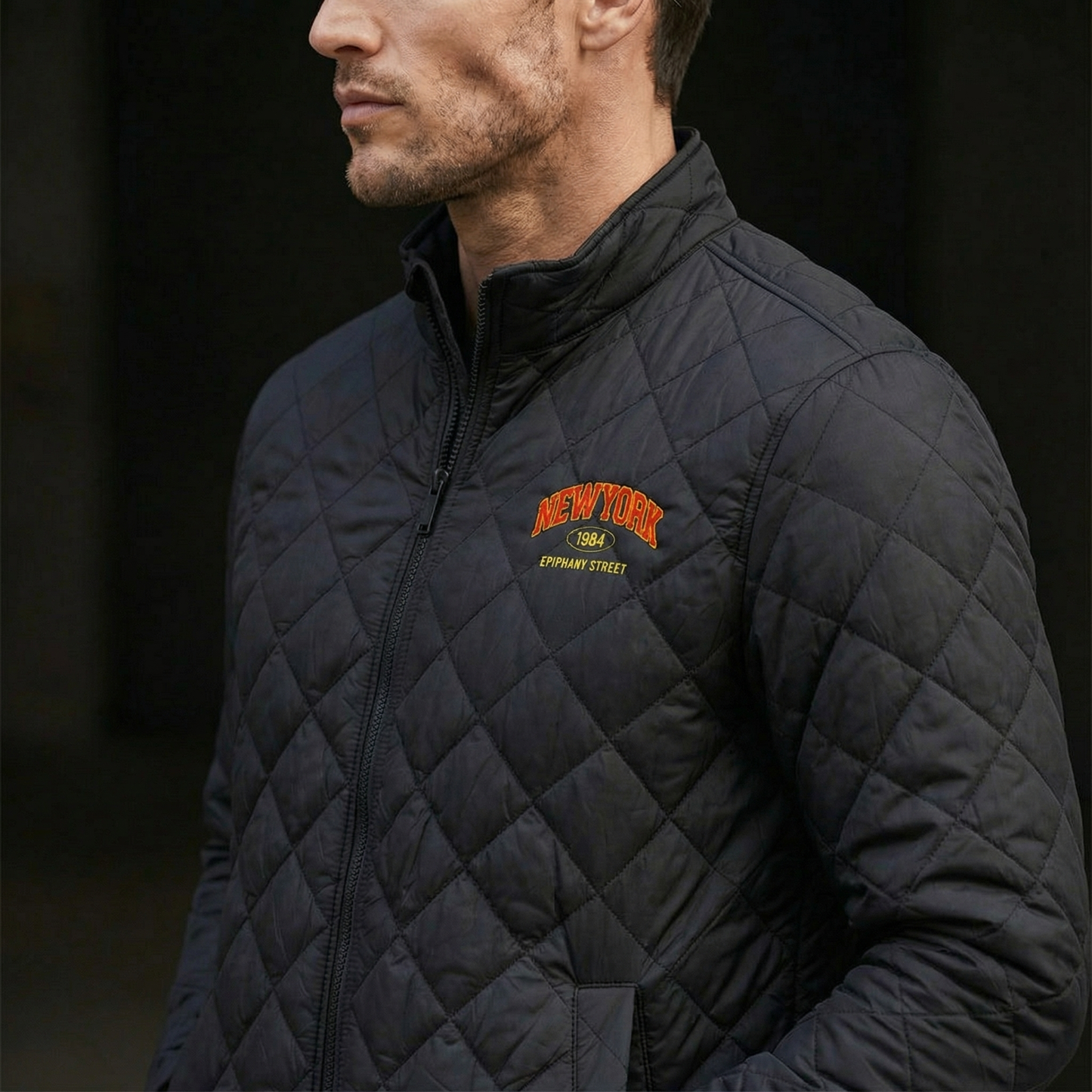 Man wearing a black quilted jacket with 'New York' logo on a dark background