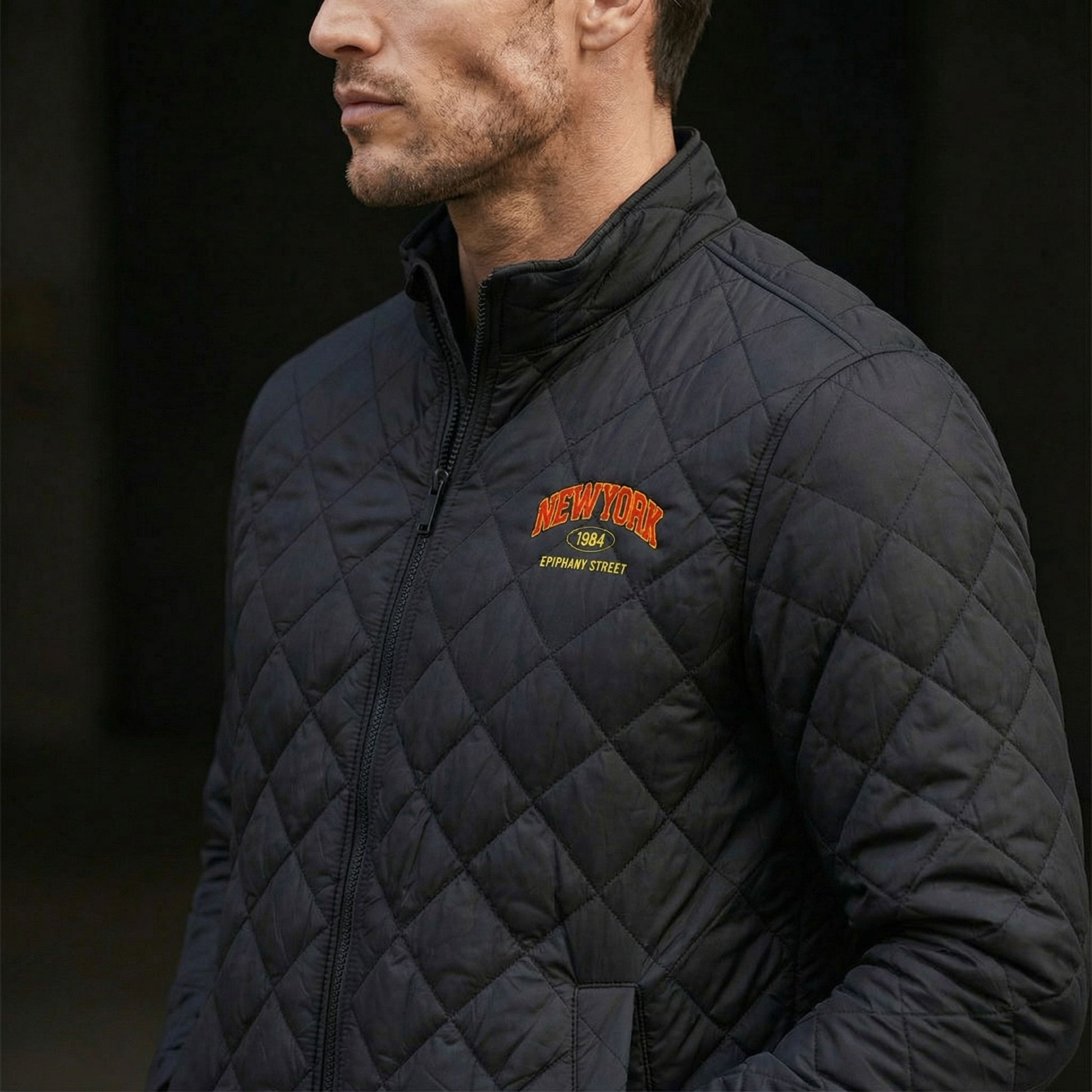 Man wearing a black quilted jacket with 'New York' logo on a dark background