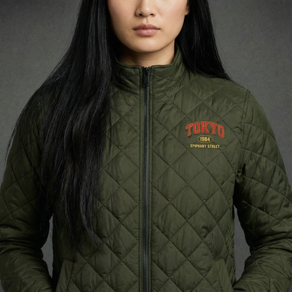 Person wearing a green quilted jacket with 'Tokyo 884' text on a gray background