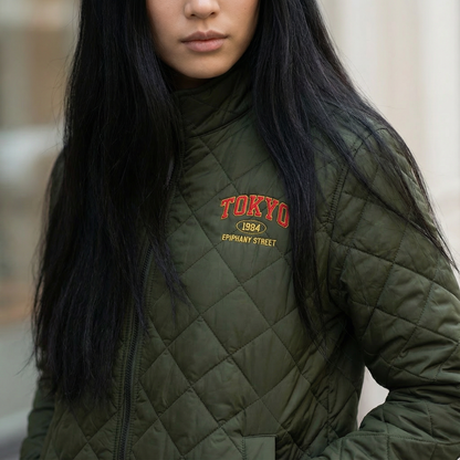 Person wearing a green quilted jacket with 'TOKYO 1984' text.